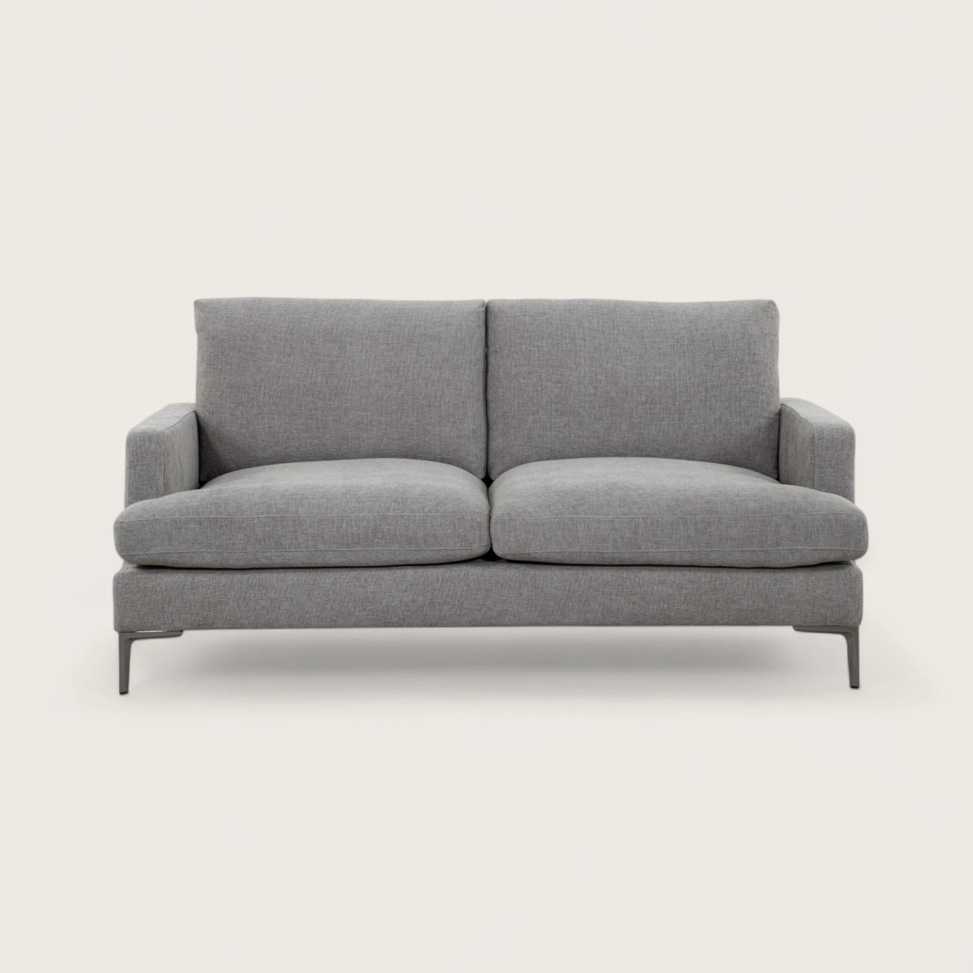 Il divano 2 posti è rivestito in tessuto tortora, con una seduta ampia completata da due cuscini pieni. Il design moderno, linee pulite e piedini in metallo conferiscono stabilità e un tocco di stile contemporaneo, rendendo il divano adatto a soggiorni eleganti e funzionali.