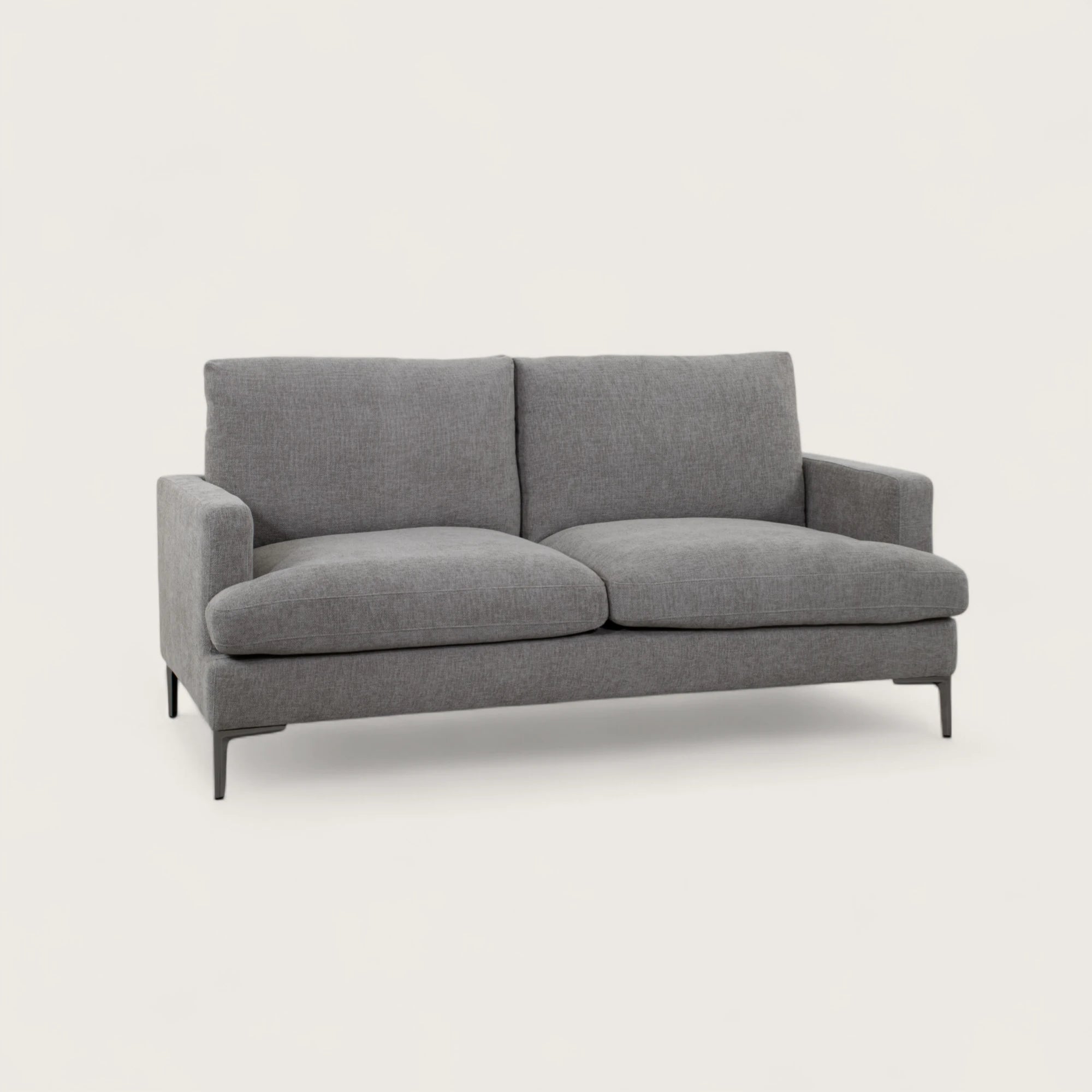 Il divano 2 posti è rivestito in tessuto tortora, con una seduta ampia completata da due cuscini pieni. Il design moderno, linee pulite e piedini in metallo conferiscono stabilità e un tocco di stile contemporaneo, rendendo il divano adatto a soggiorni eleganti e funzionali.