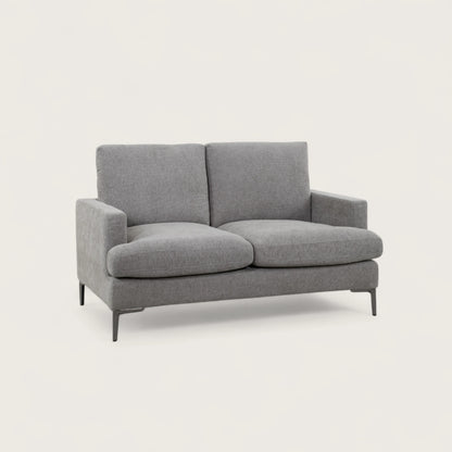 Divano 2 posti tortora in tessuto di alta qualità, con seduta ampia e due cuscini pieni. Design moderno con linee pulite e piedini in metallo per stile e stabilità.